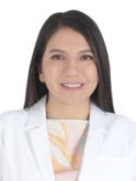 A young Peruvian woman with long brown hair wears a light orange patterned blouse and a white doctor's coat and smiles at the camera in front of a white background.
